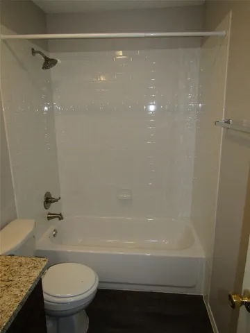 a bathroom with a granite countertop bathtub shower sink vanity and toilet