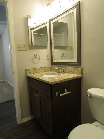 a bathroom with a granite countertop sink toilet and mirror