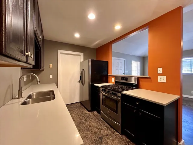 a kitchen with granite countertop stainless steel appliances a sink stove and refrigerator