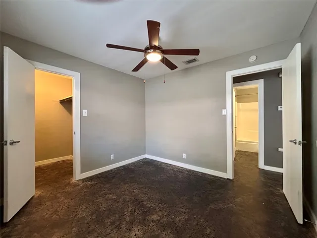 an empty room with closet and a chandelier fan