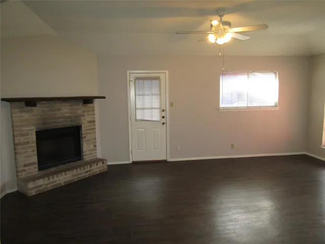 an empty room with wooden floor a fireplace and a window