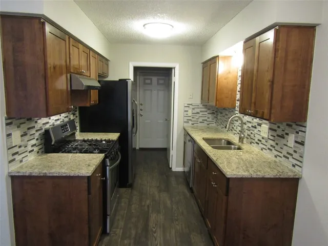 a kitchen with a granite countertop sink a stove and refrigerator