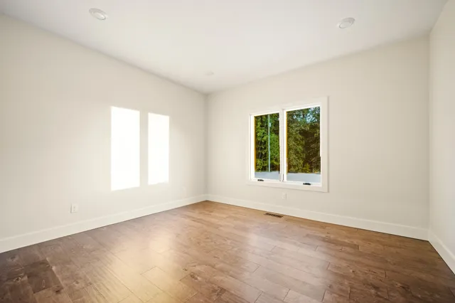an empty room with wooden floor and windows