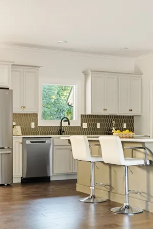 a kitchen with a stove a sink and white cabinets with wooden floors