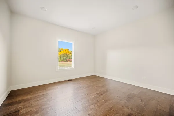 an empty room with a window and wooden floor