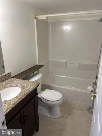 a bathroom with a granite countertop sink a toilet and shower
