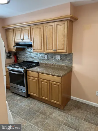 a kitchen with granite countertop a sink stove and cabinets
