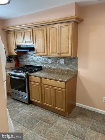 a kitchen with granite countertop a sink stove and cabinets