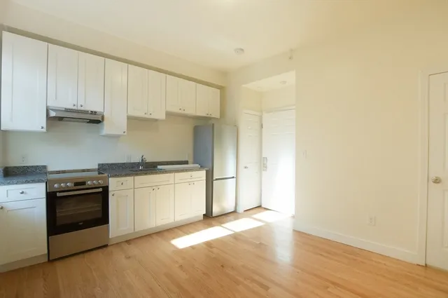 a kitchen with granite countertop white cabinets and stainless steel appliances