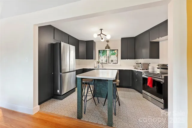 a kitchen with stainless steel appliances kitchen island granite countertop a refrigerator a stove a sink and a dining table with wooden floor