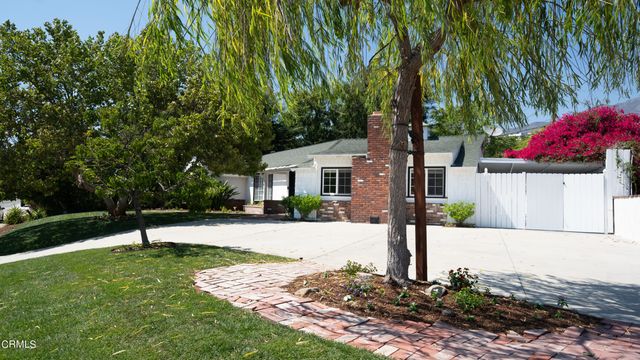 a front view of a house with a yard and tree s
