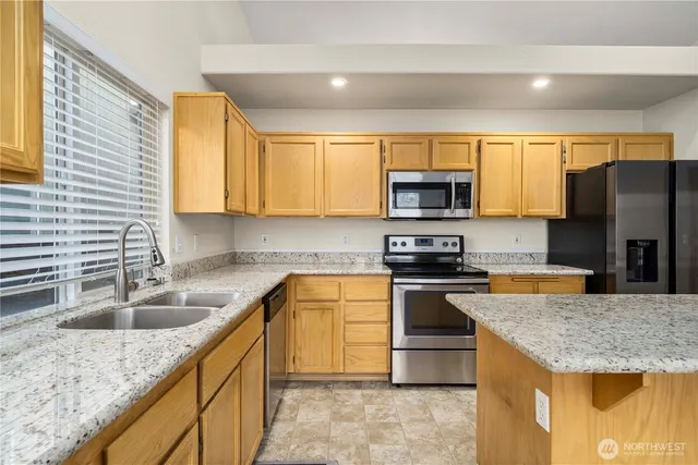 a kitchen with granite countertop a sink a stove and a microwave
