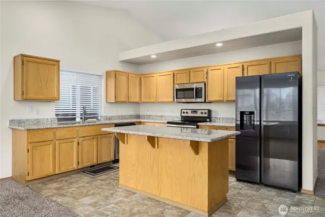 a kitchen with stainless steel appliances granite countertop a refrigerator a stove a sink and a microwave