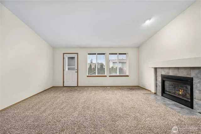 an empty room with windows and fireplace