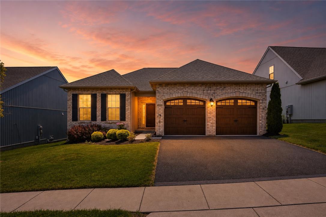 4120 Eveningstar Road Emmaus, PA 18049 - Photo 1 of 62 Golden hour illuminates a charming brick home with a double garage and tidy front landscaping.