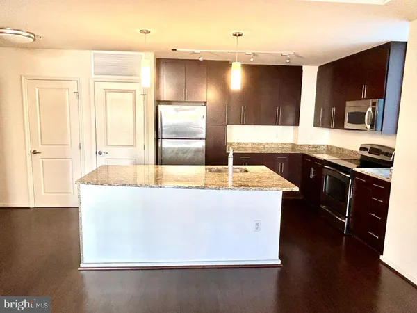 a large kitchen with a large counter top space appliances and wooden floor