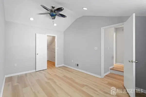an empty room with wooden floor and a ceiling fan