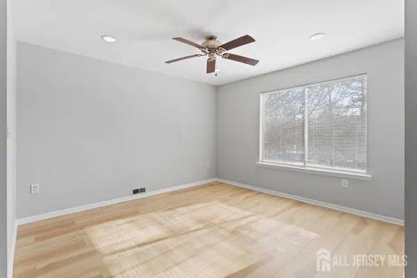 an empty room with windows and fan