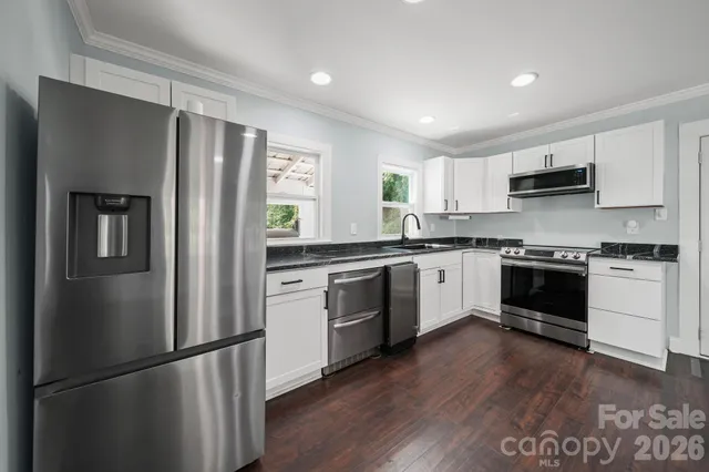 a kitchen with a refrigerator a stove top oven a sink and cabinets