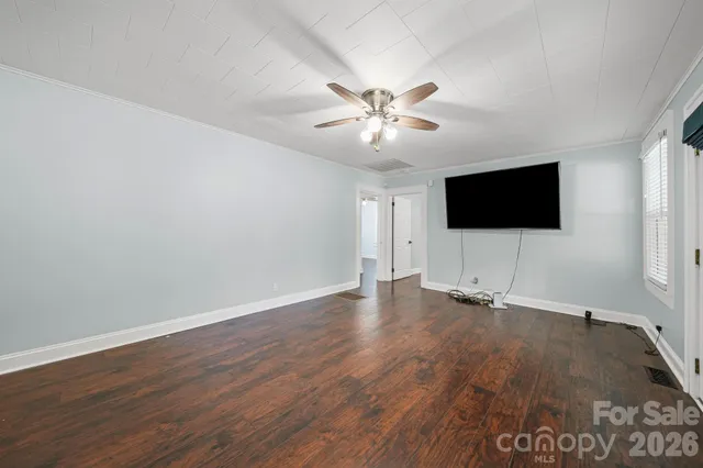 an empty room with wooden floor and a flat screen tv