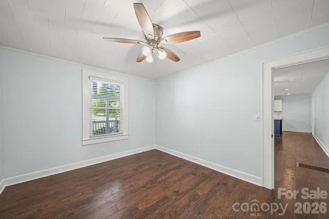 an empty room with wooden floor fan and windows