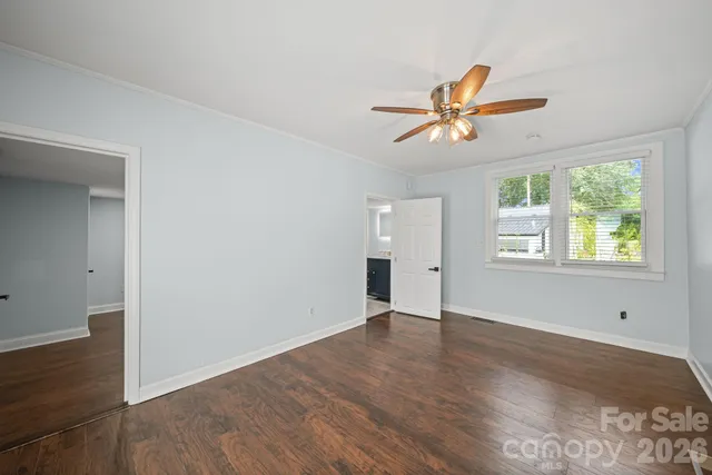 an empty room with wooden floor ceiling fan and windows