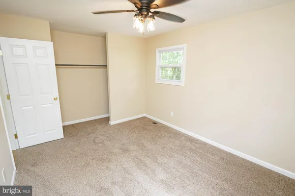 an empty room with a window and a ceiling fan