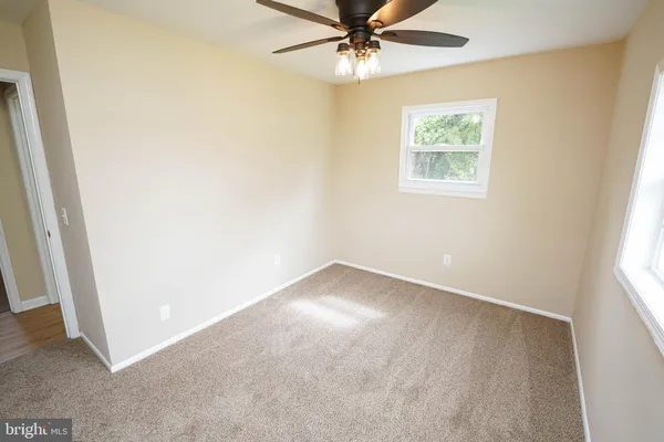 an empty room with a window and a fan