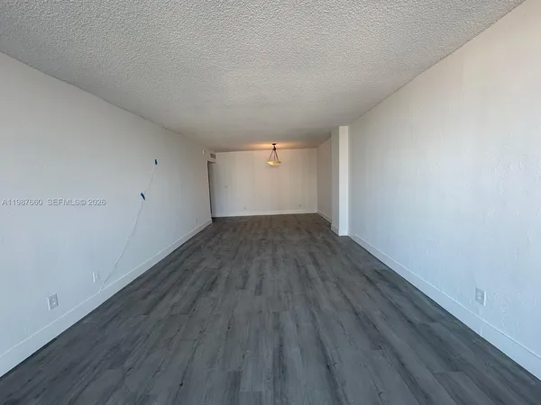 a view of empty room with wooden floor and window