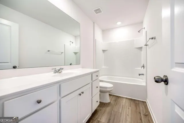 a bathroom with a double vanity sink toilet mirror and shower