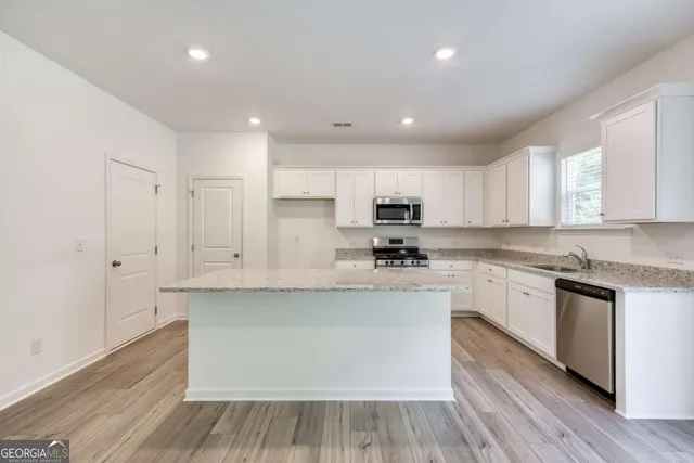 a large kitchen with stainless steel appliances granite countertop a stove a sink and white cabinets