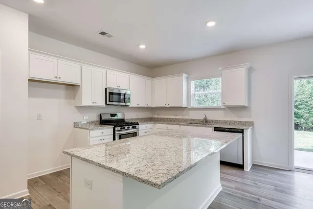a kitchen with granite countertop a sink stove and cabinets