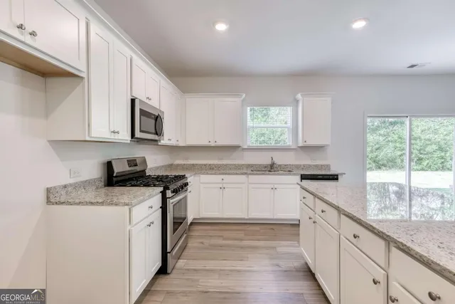 a kitchen with granite countertop white cabinets and white appliances