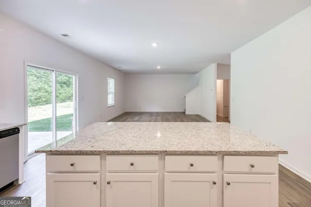 a kitchen with granite countertop white cabinets and a window