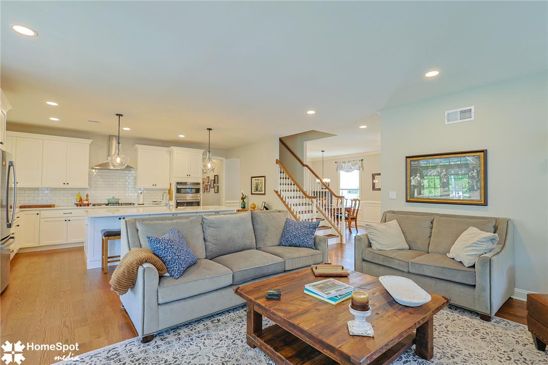 An open-concept living space integrates a well-appointed kitchen and a cozy seating area, featuring rich hardwood floors and recessed lighting.