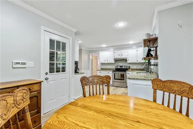 a kitchen with stainless steel appliances granite countertop a stove top oven a sink dishwasher and white cabinets with wooden floor