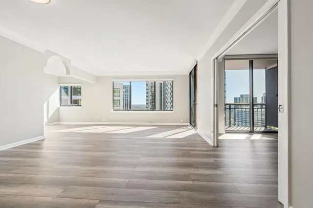 a view of an empty room with wooden floor and a window
