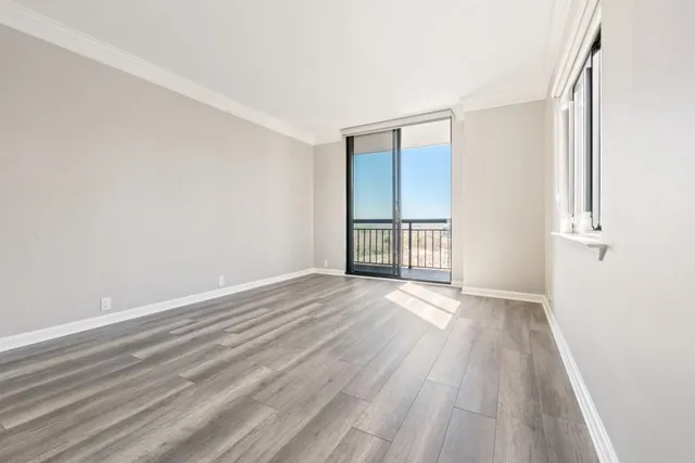 an empty room with wooden floor and windows