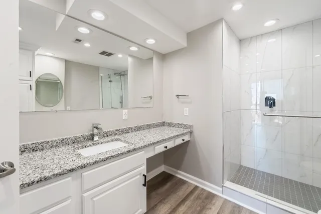 a bathroom with a granite countertop sink a mirror and a shower