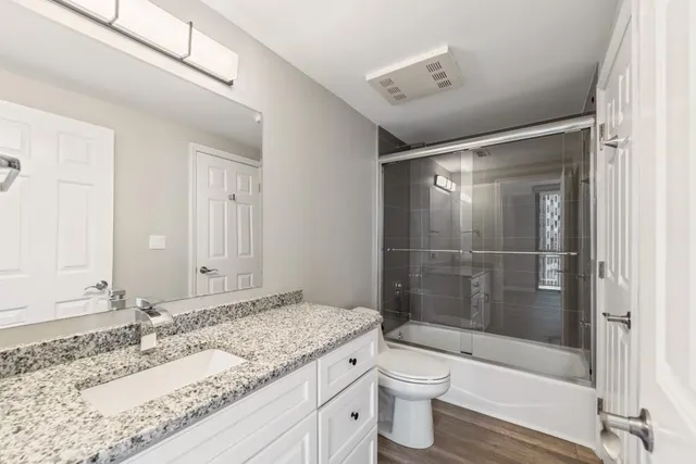 a bathroom with a granite countertop sink a toilet and shower
