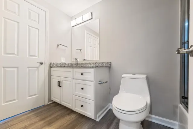 a bathroom with a granite countertop toilet sink and mirror