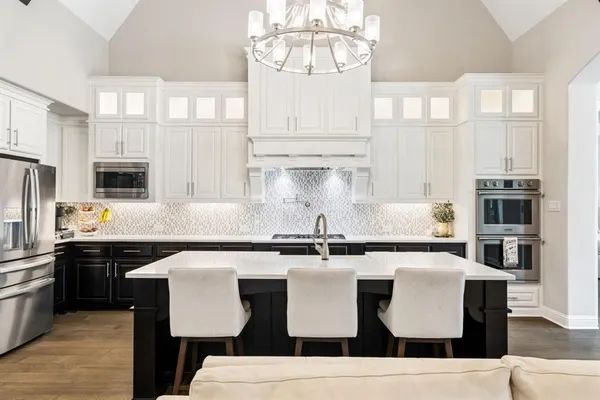 a kitchen with stainless steel appliances granite countertop a sink a stove and white cabinets