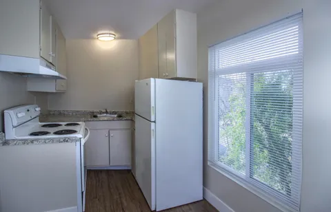 a kitchen with a refrigerator a stove a washer dryer and white cabinets