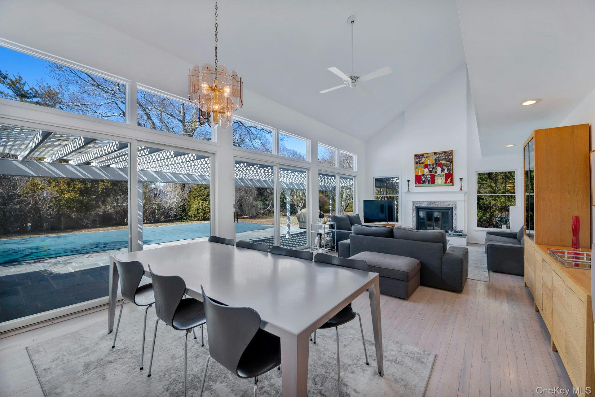 94 South Country Road Remsenburg, NY 11960 - Photo 4 of 40 Ideal entertaining Space: Living room and dining area flanked by wall to wall glass sliders to patio, pool, tennis with a wood burning fireplace, drenched in light and art