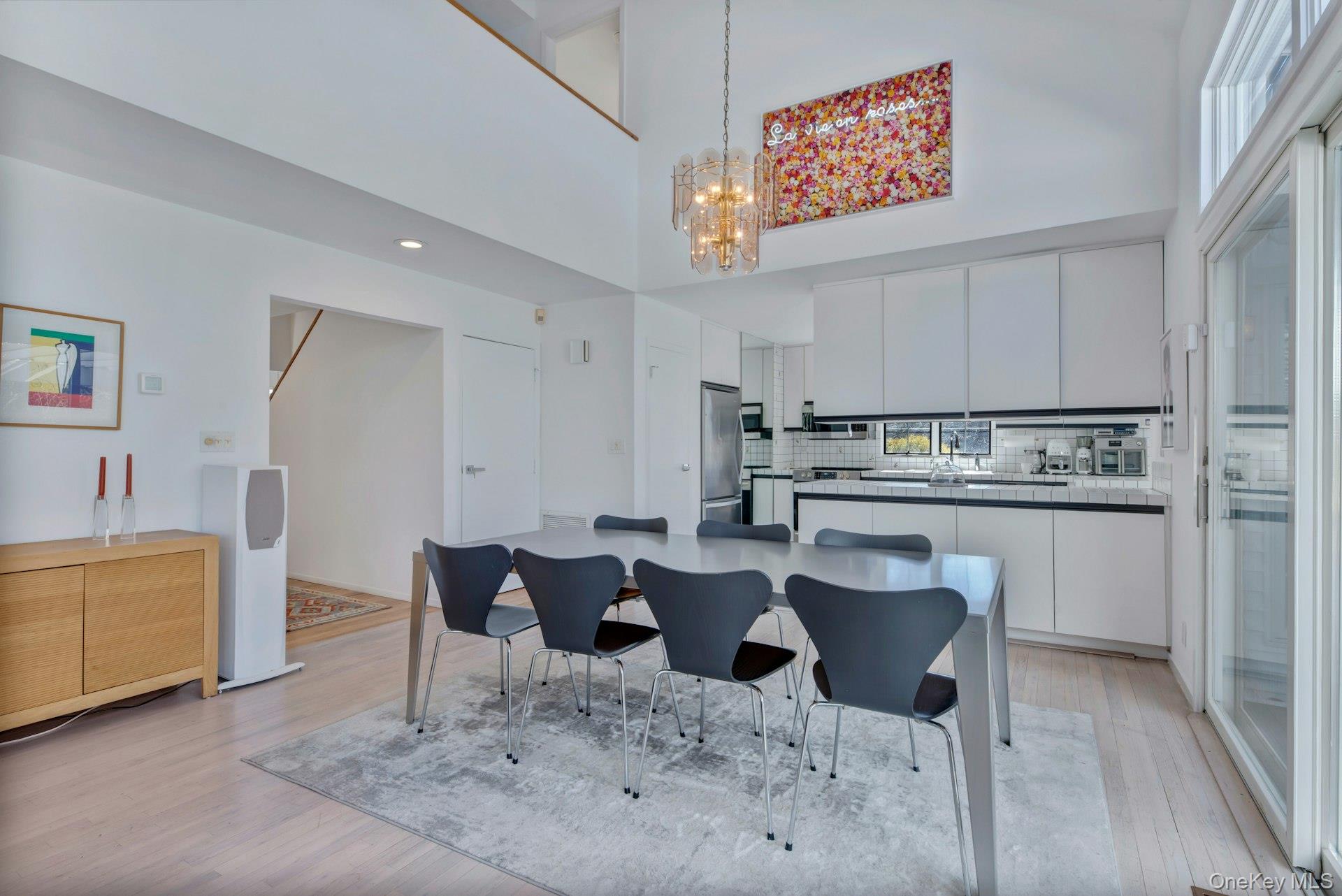 94 South Country Road Remsenburg, NY 11960 - Photo 10 of 40 Great room Dining area open to kitchen island with a notable chandelier