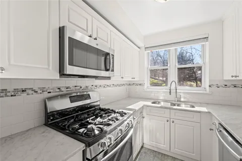 a kitchen with granite countertop a stove sink and microwave