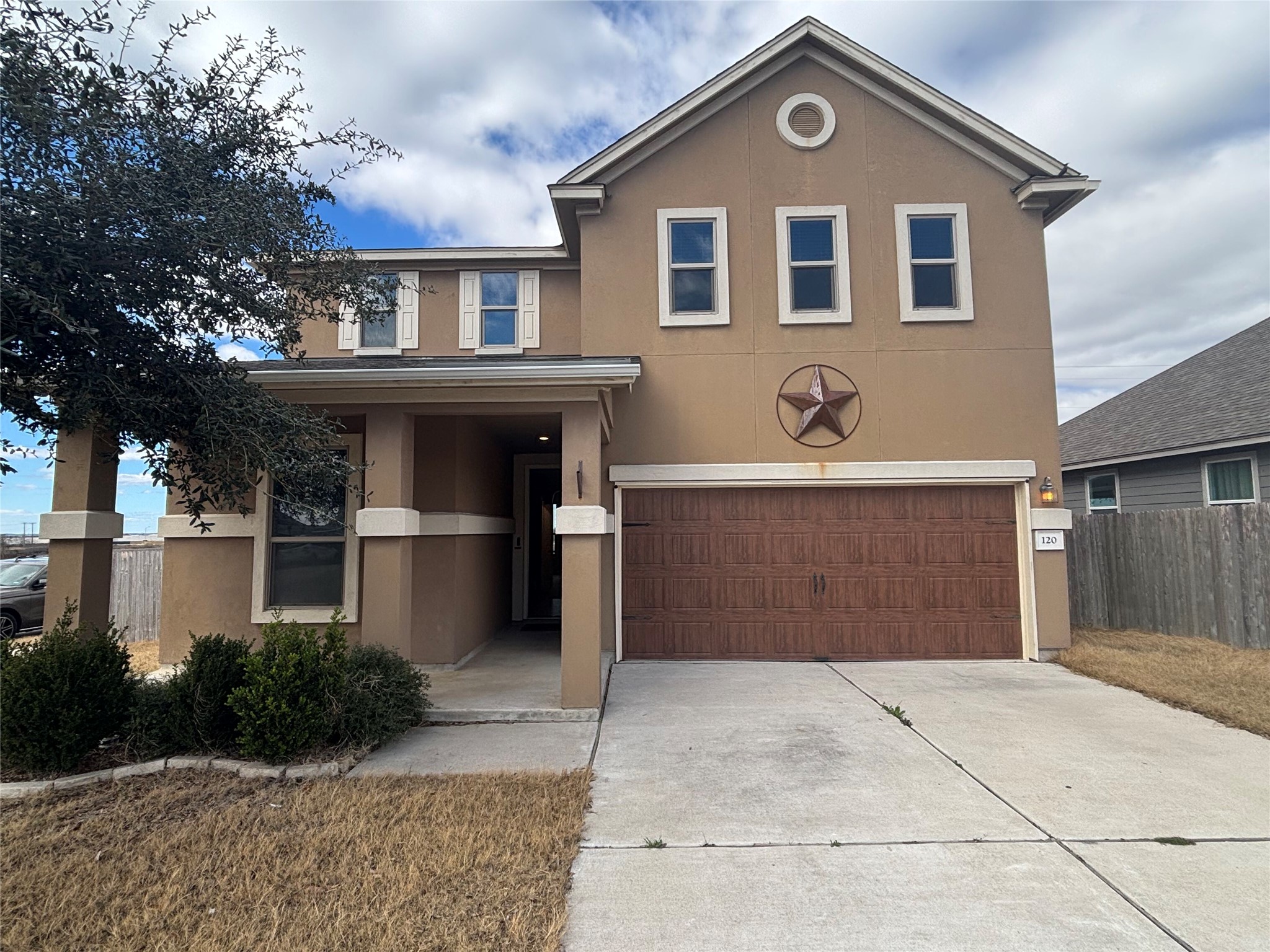Traditional home featuring stucco siding, an attached garage, and driveway