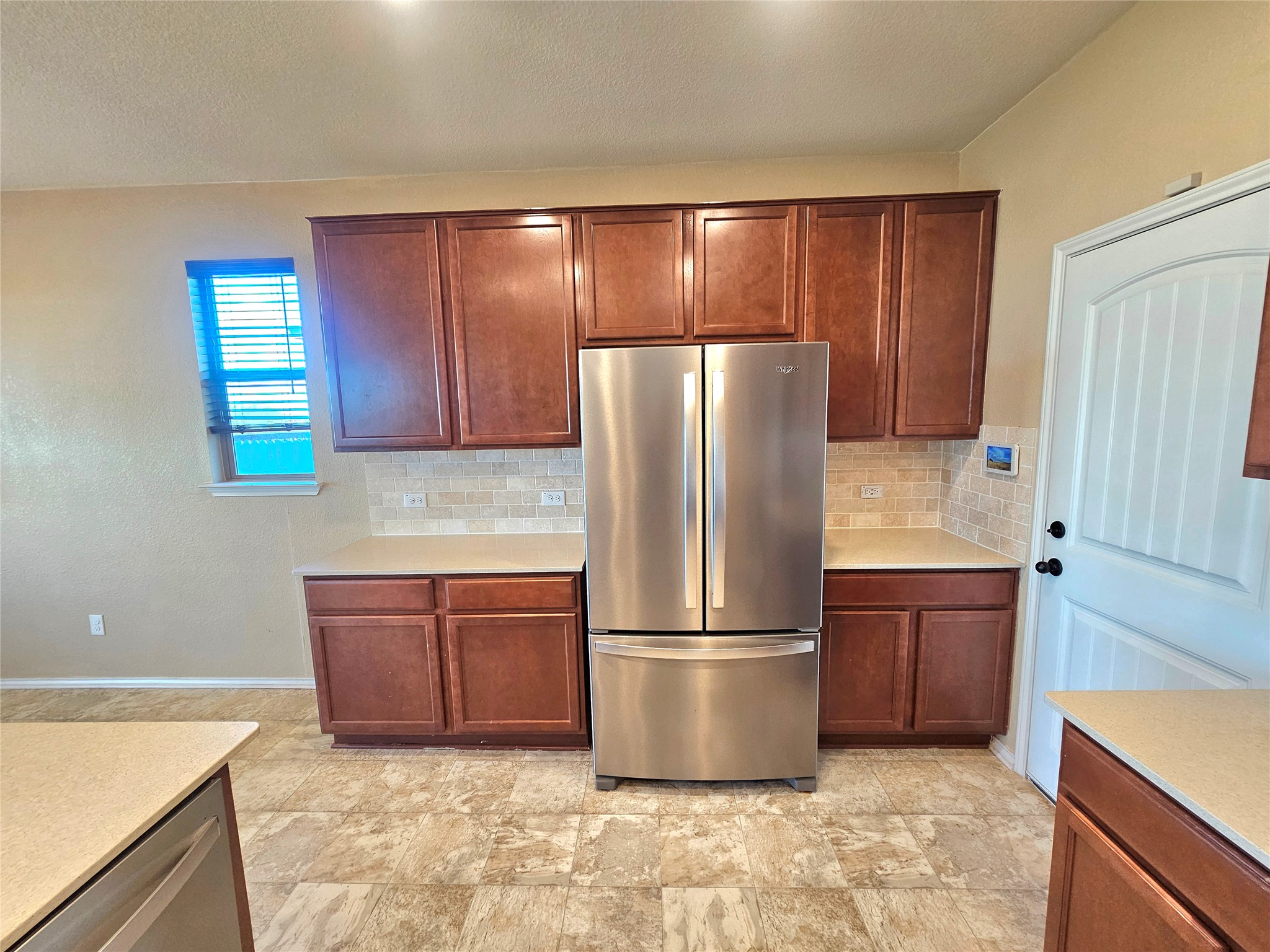 120 Schuylerville Drive Elgin, TX 78621 - Photo 14 of 29 Kitchen featuring appliances with stainless steel finishes, decorative backsplash, a textured ceiling, stone finish flooring, and brown cabinets