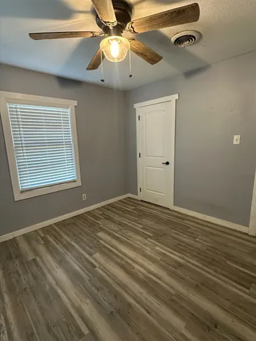 en empty room with wooden floor fan and windows