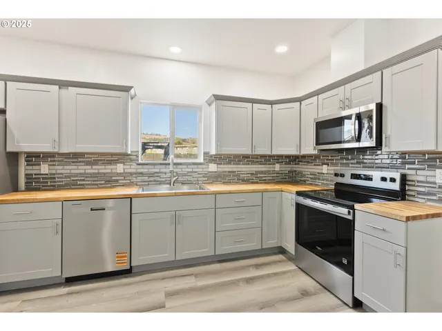 a kitchen with stainless steel appliances granite countertop a stove a sink and a microwave